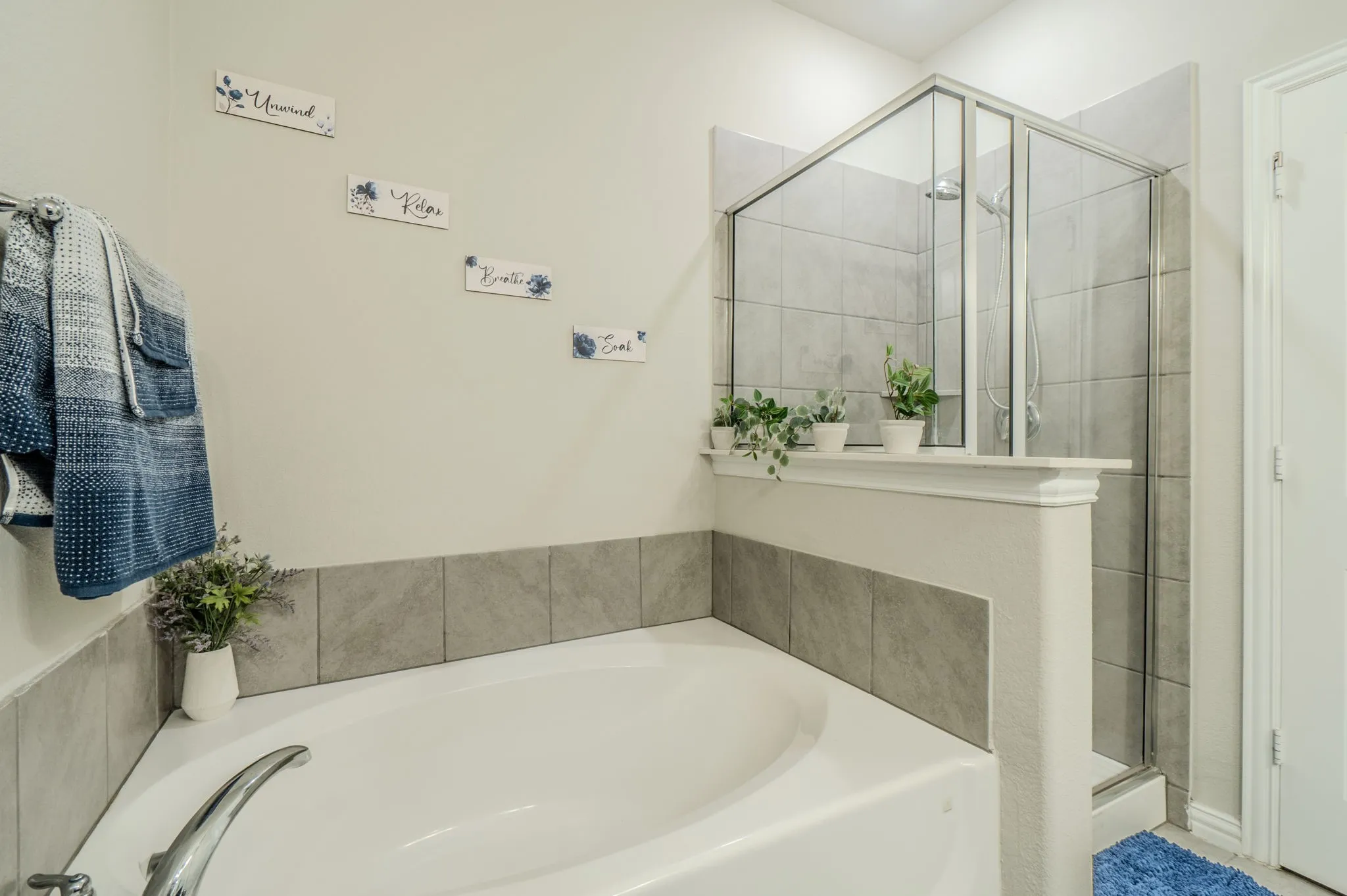 Primary bathroom featuring corner soaking tub with a curved basin and chrome fixture, complemented by a separate glass-enclosed shower with tile surround