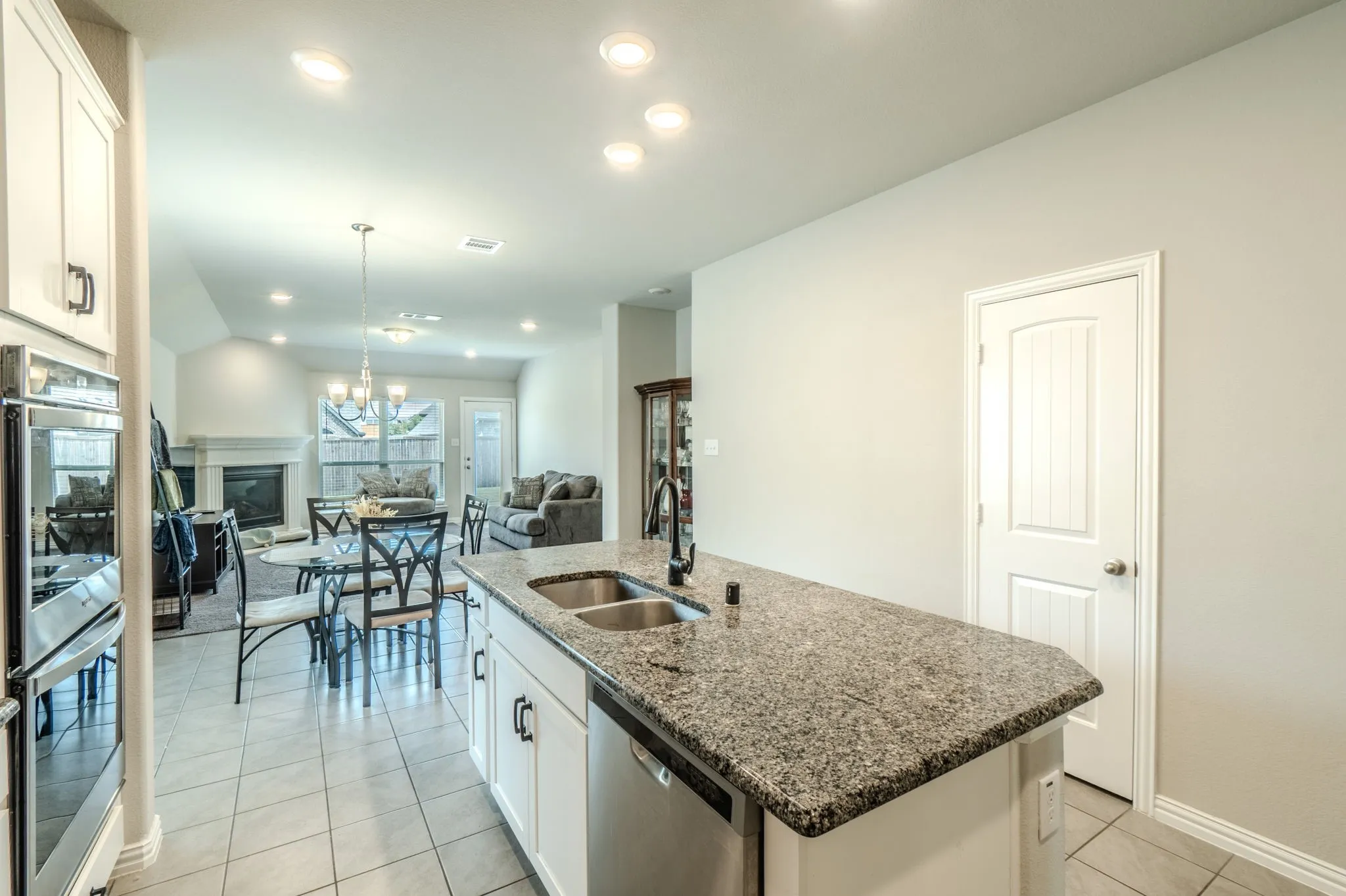 Kitchen island with granite countertop and double stainless steel sink, View of the breakfast area and living room from the kitchen.