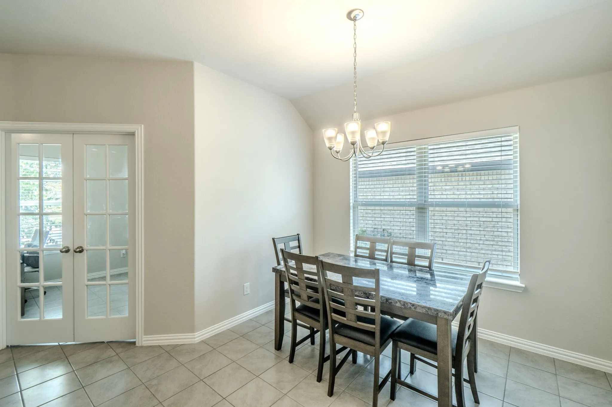 Dining room featuring large windows with blinds, a multi-light chandelier, and light-toned walls