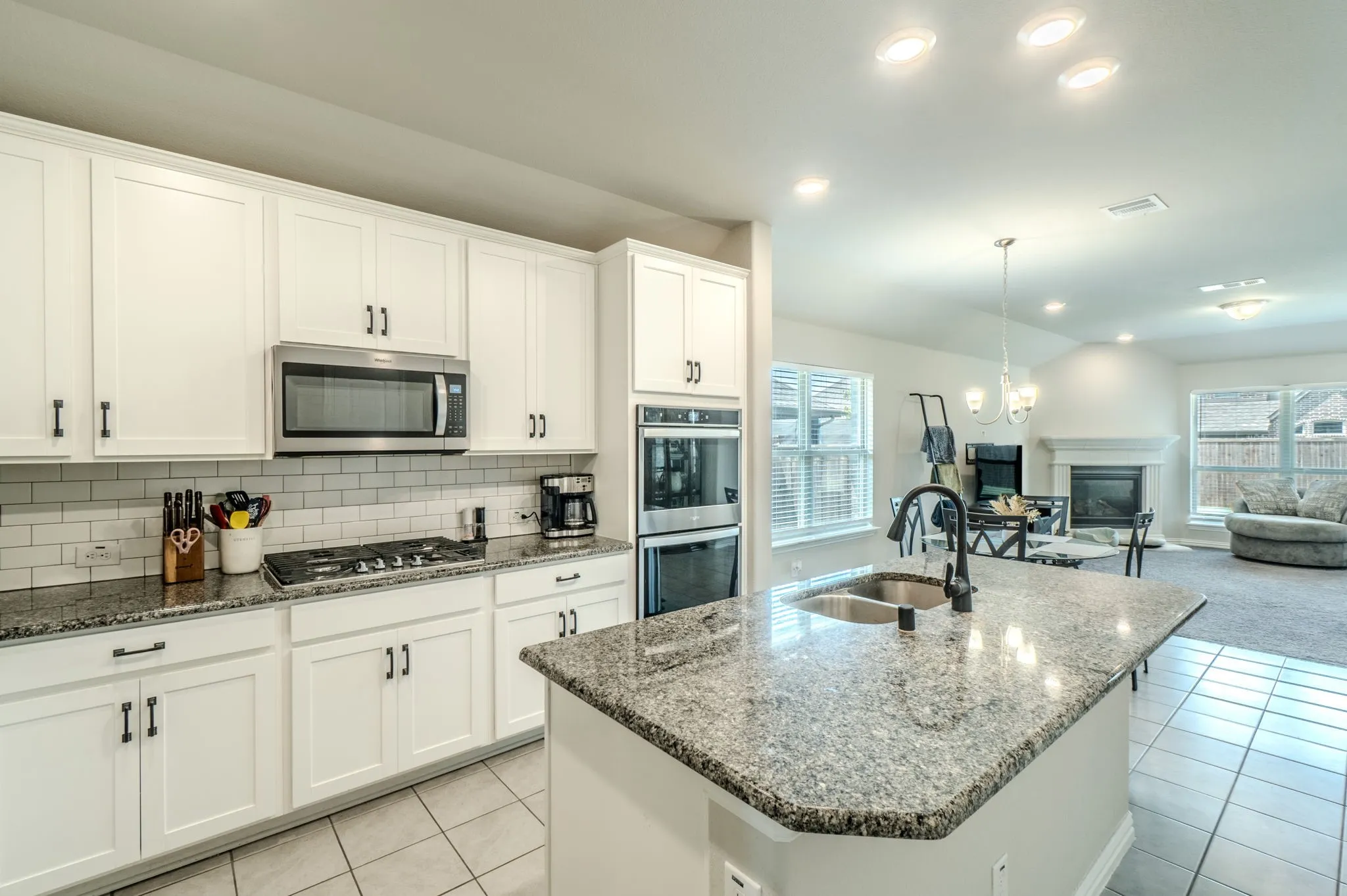 Kitchen featuring white cabinetry, stainless steel appliances, a gas cooktop, subway tile backsplash, and granite countertops