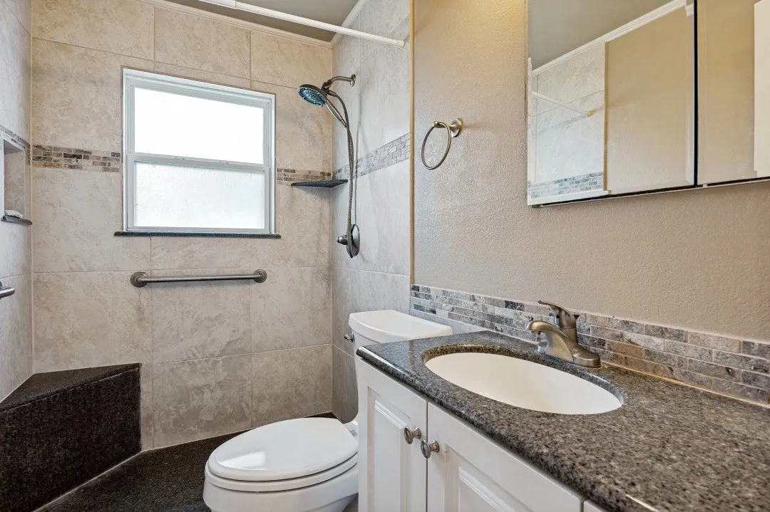 Tiled shower with a window, built-in bench, and grab bars