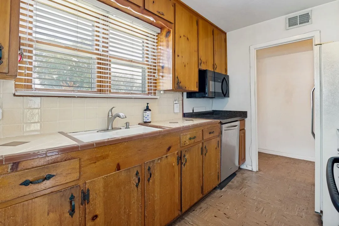 Kitchen featuring wood cabinetry, tile backsplash, a stainless steel dishwasher, and a  microwave