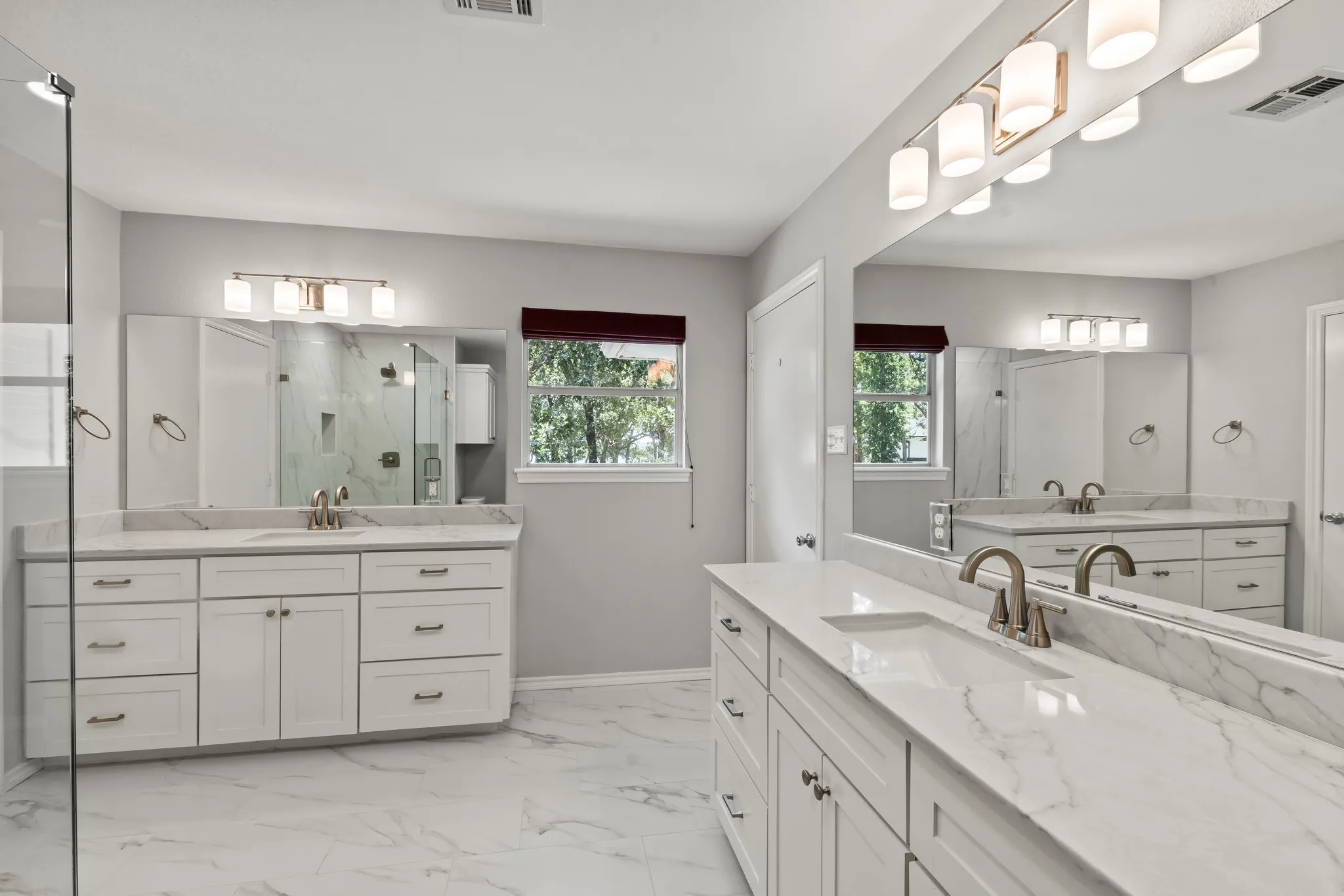 Generous sized primary ensuite bath with dual vanities, modern tile and quartz finishes, and walk in shower, plus spacious walk in closet.