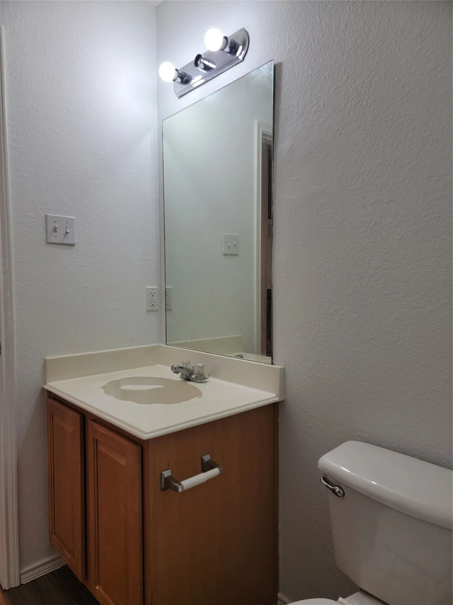 Bathroom featuring a wood-finish vanity with an integrated sink and countertop, chrome faucet, and mirrored medicine cabinet