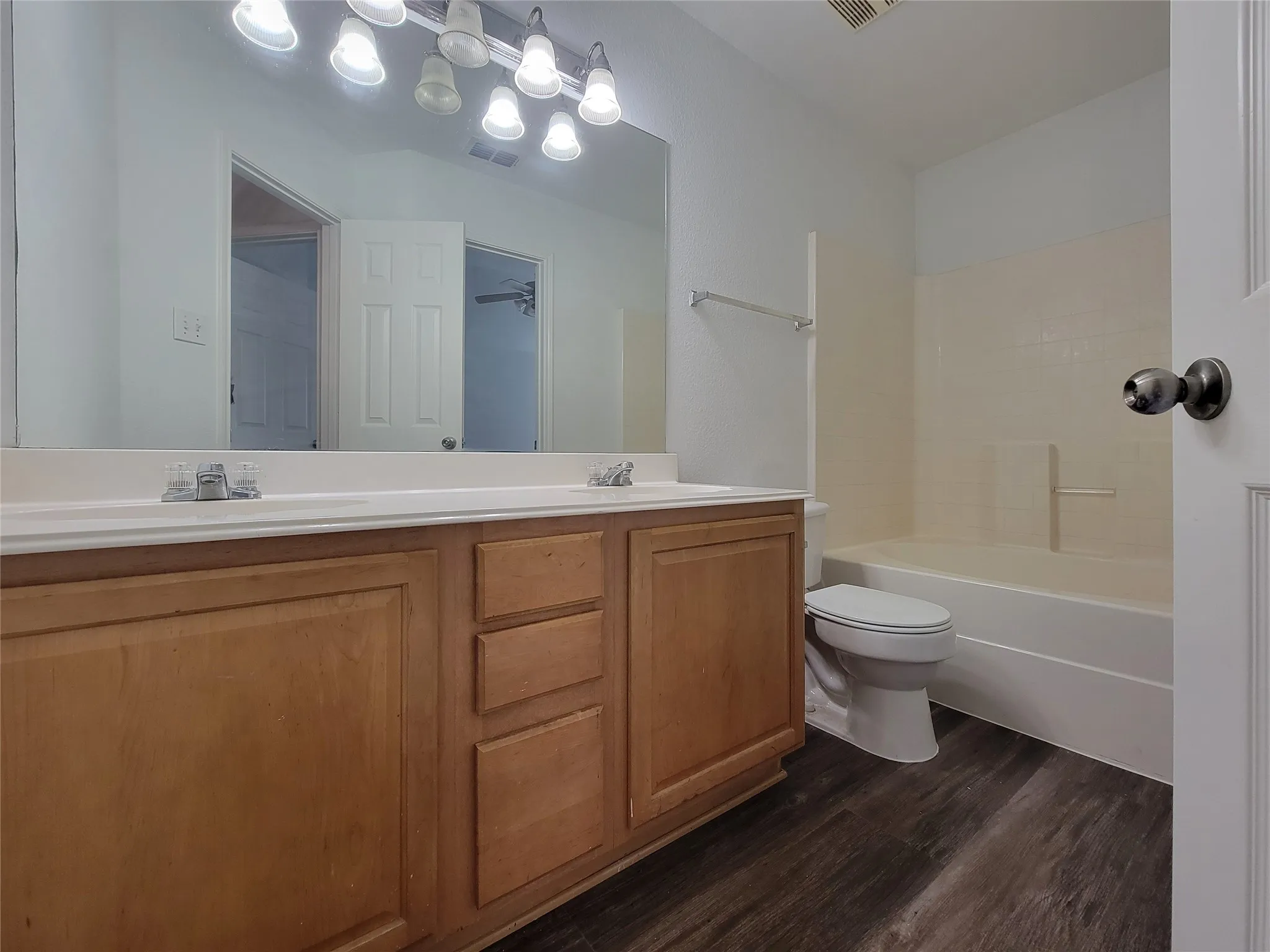 Bathroom featuring a dual vanity with light wood-finish cabinetry, white countertops, and chrome faucets
