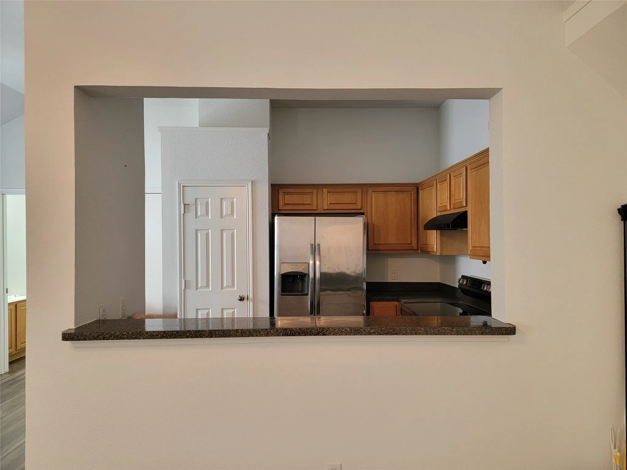 Kitchen pass-through featuring a granite-finish breakfast bar