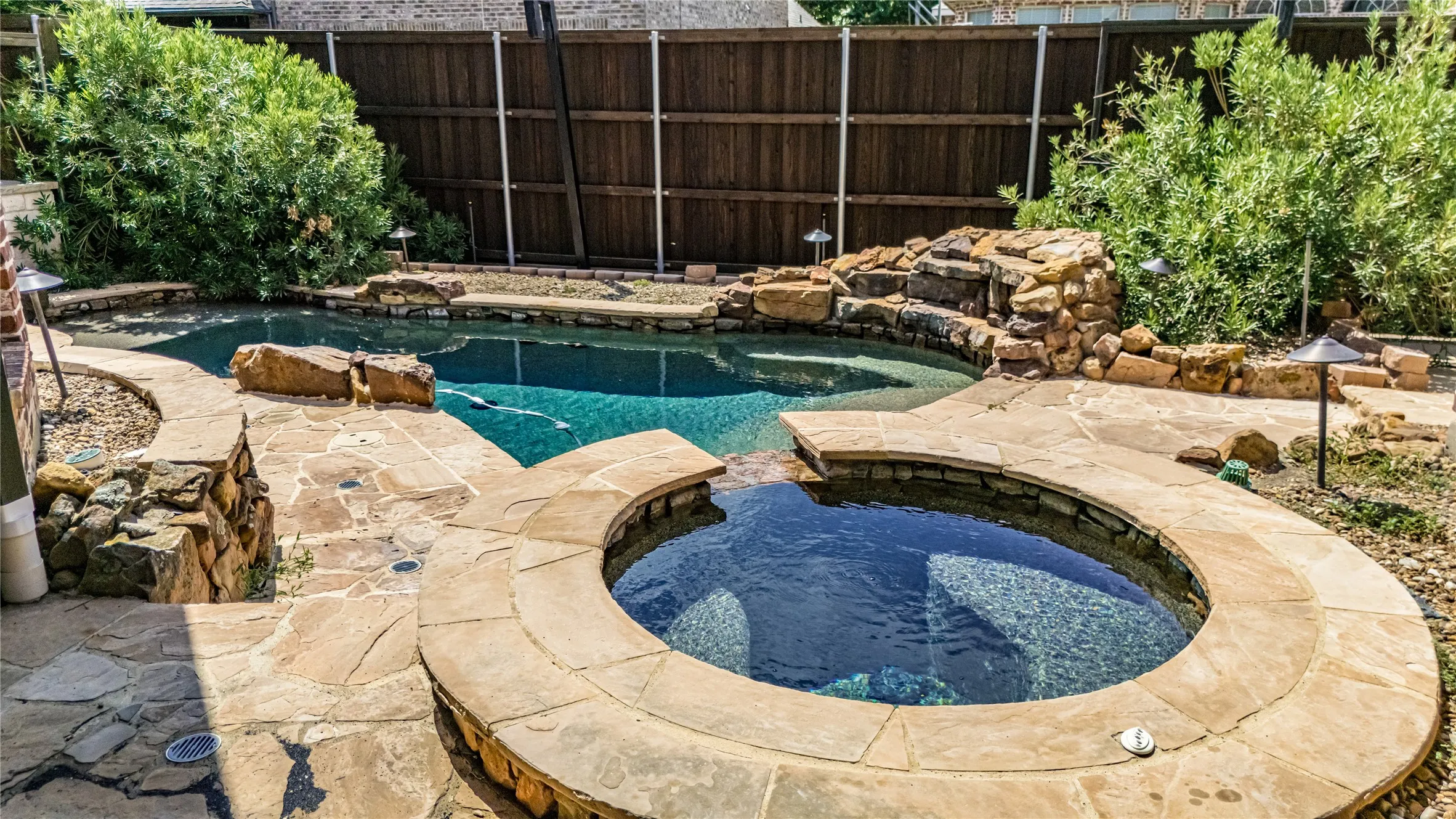 Resort-style backyard featuring a stone-lined pool and circular spa