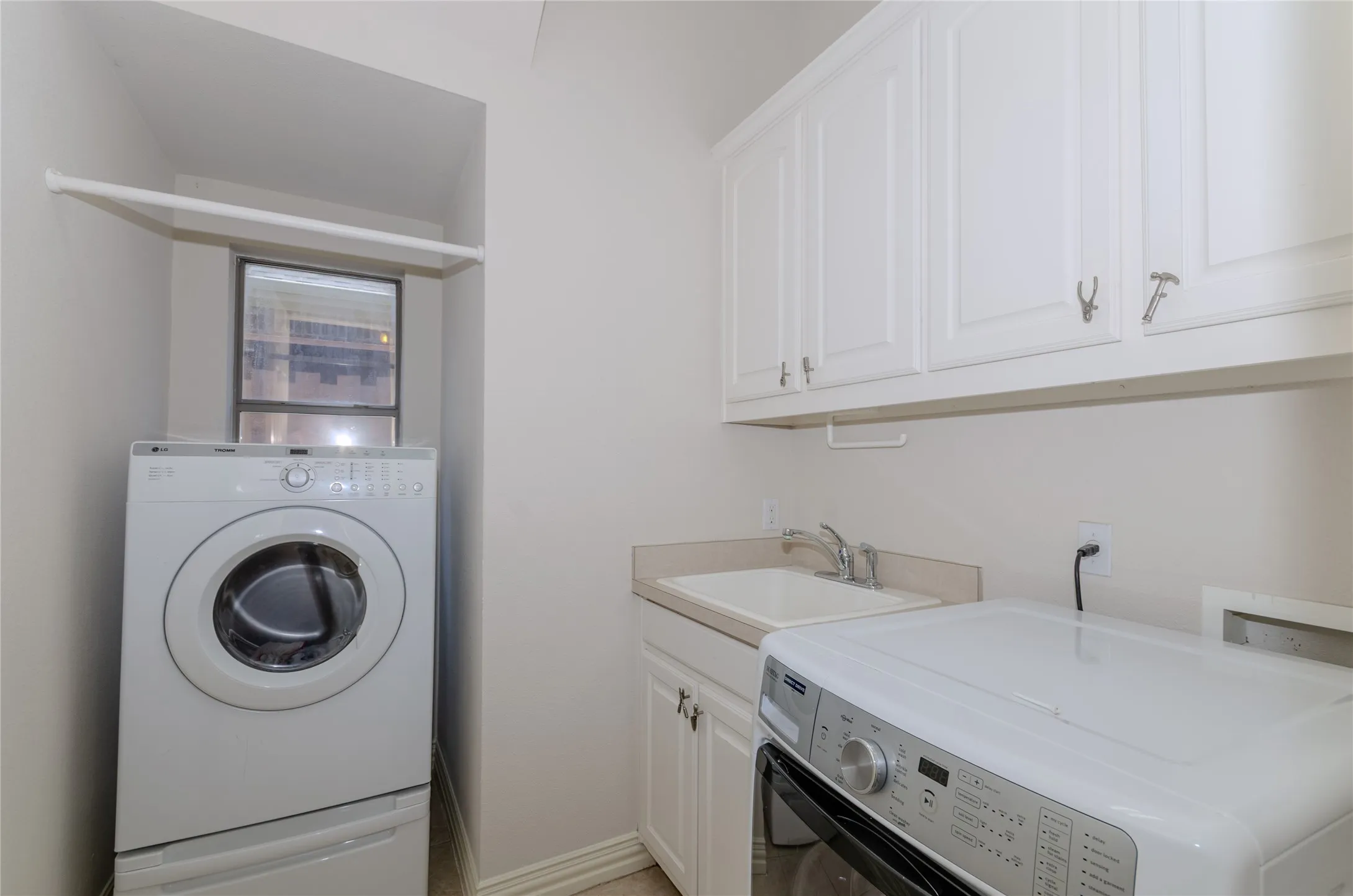 Laundry room with built-in cabinets, utility sink, washer and dryer