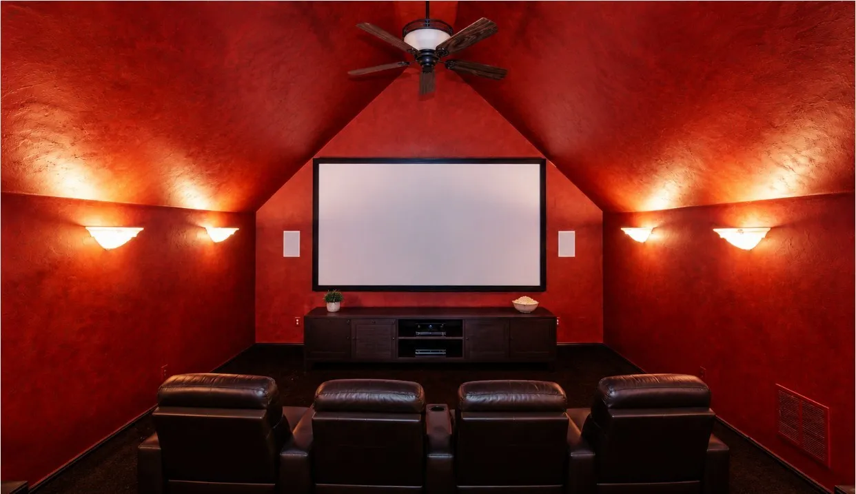 Home theater featuring carpet, vaulted ceiling, a ceiling fan, theater lighting, built-in cabinets in the back.
