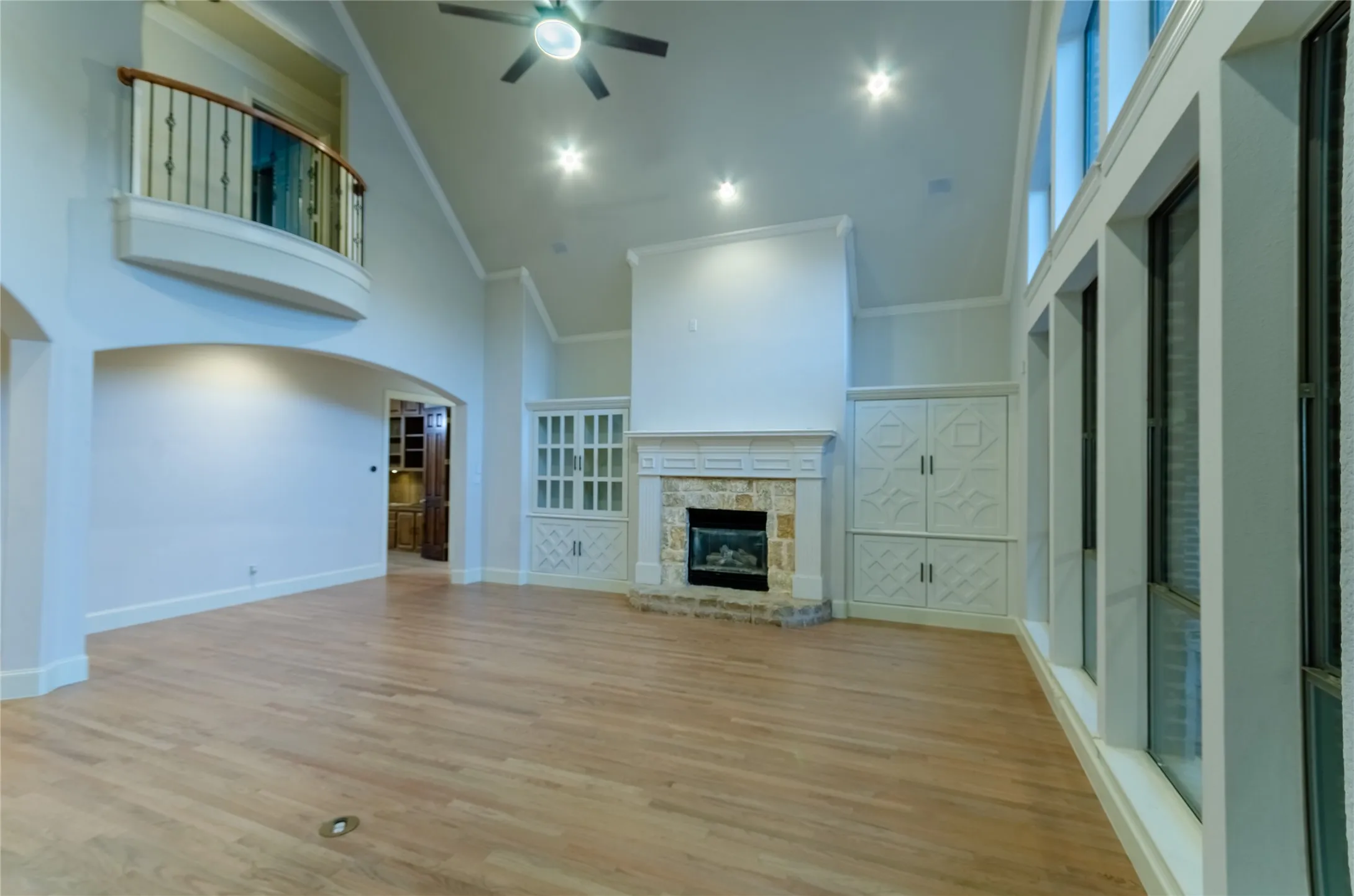 Living space featuring wood-finish flooring, a stone-clad fireplace with a decorative mantel, and built-in cabinetry