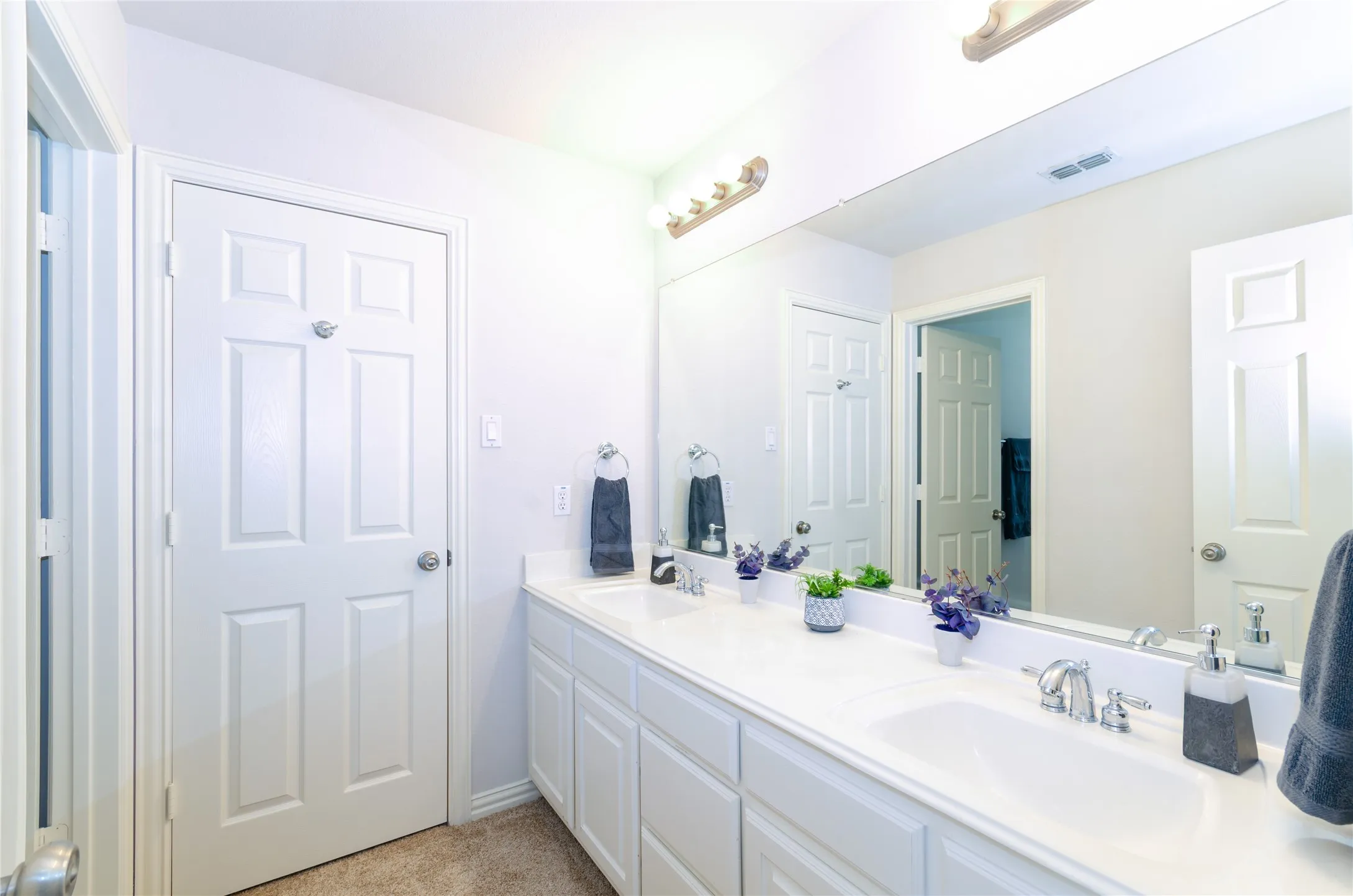 Bathroom # 4 Dual vanity with white cabinetry, integrated sinks, chrome fixtures, and a wide wall-mounted mirror