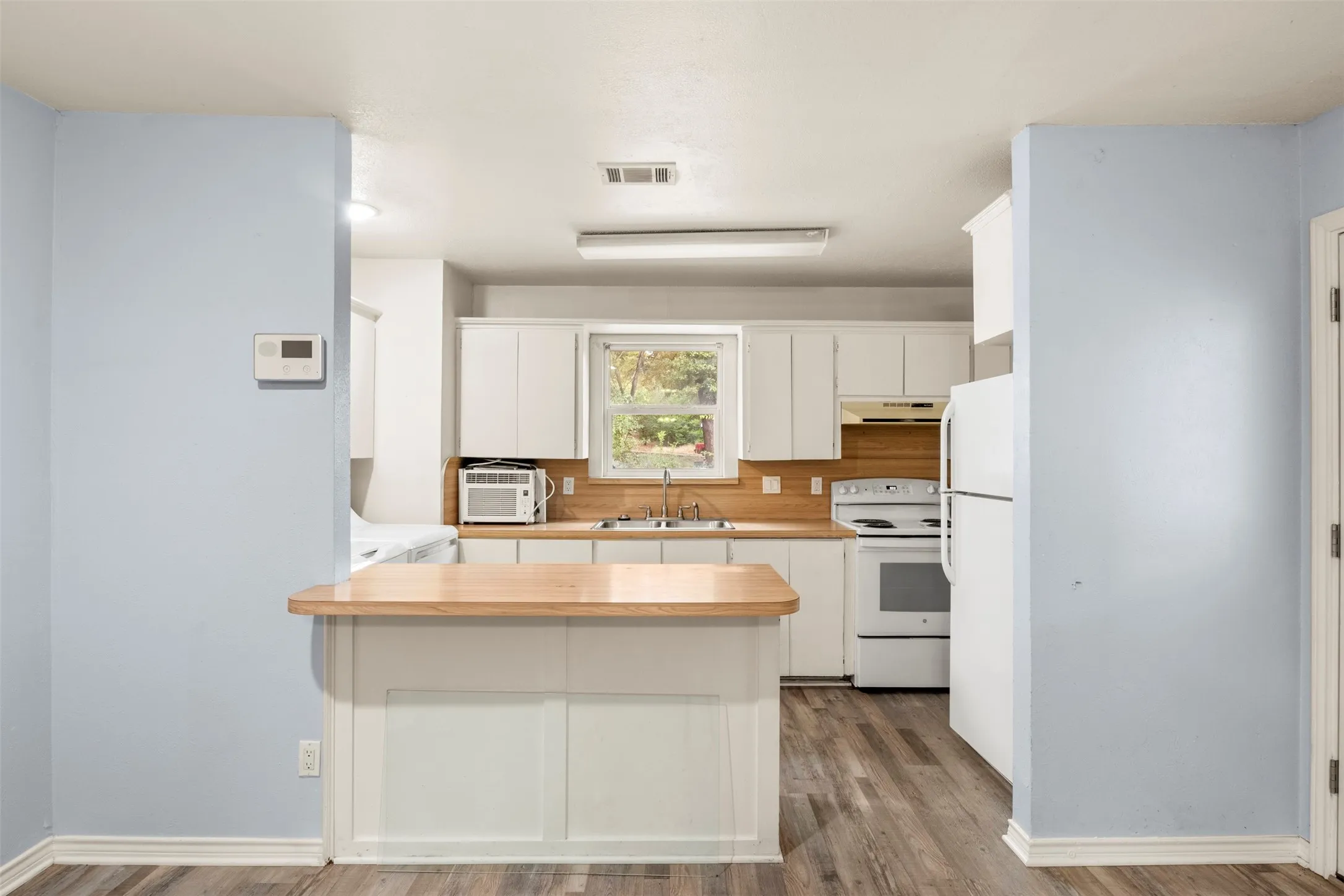 Kitchen featuring white cabinetry, wood-finish countertops, and wood-finish flooring
