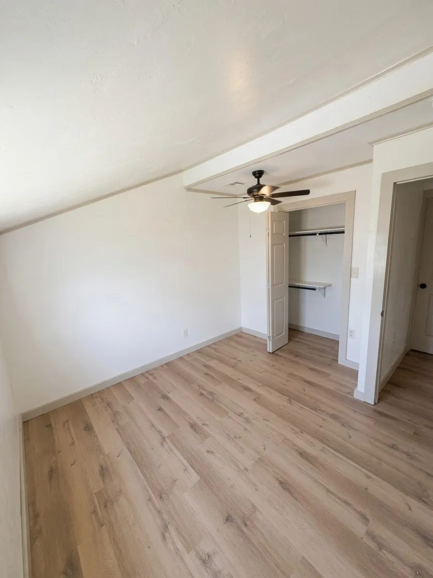 Room featuring light wood-finish flooring, white walls, and a ceiling fan with integrated lighting