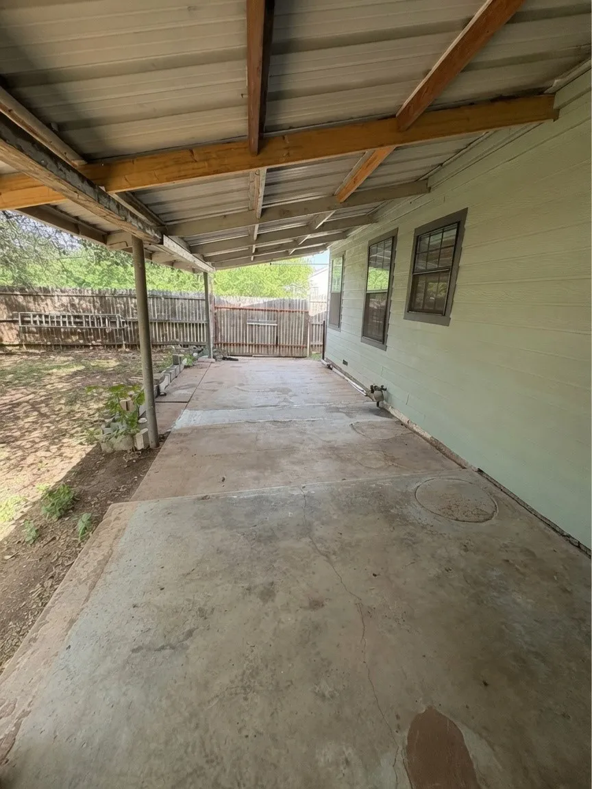 Covered concrete patio car port with a metal roof and exposed wood beams