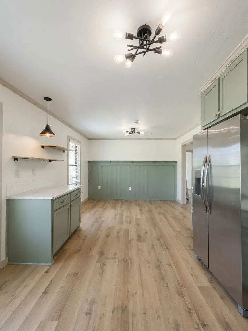 Open-concept area featuring wood-finish flooring, a stainless steel refrigerator, sage green cabinetry with a stone-finish countertop, and a contemporary ceiling light fixture