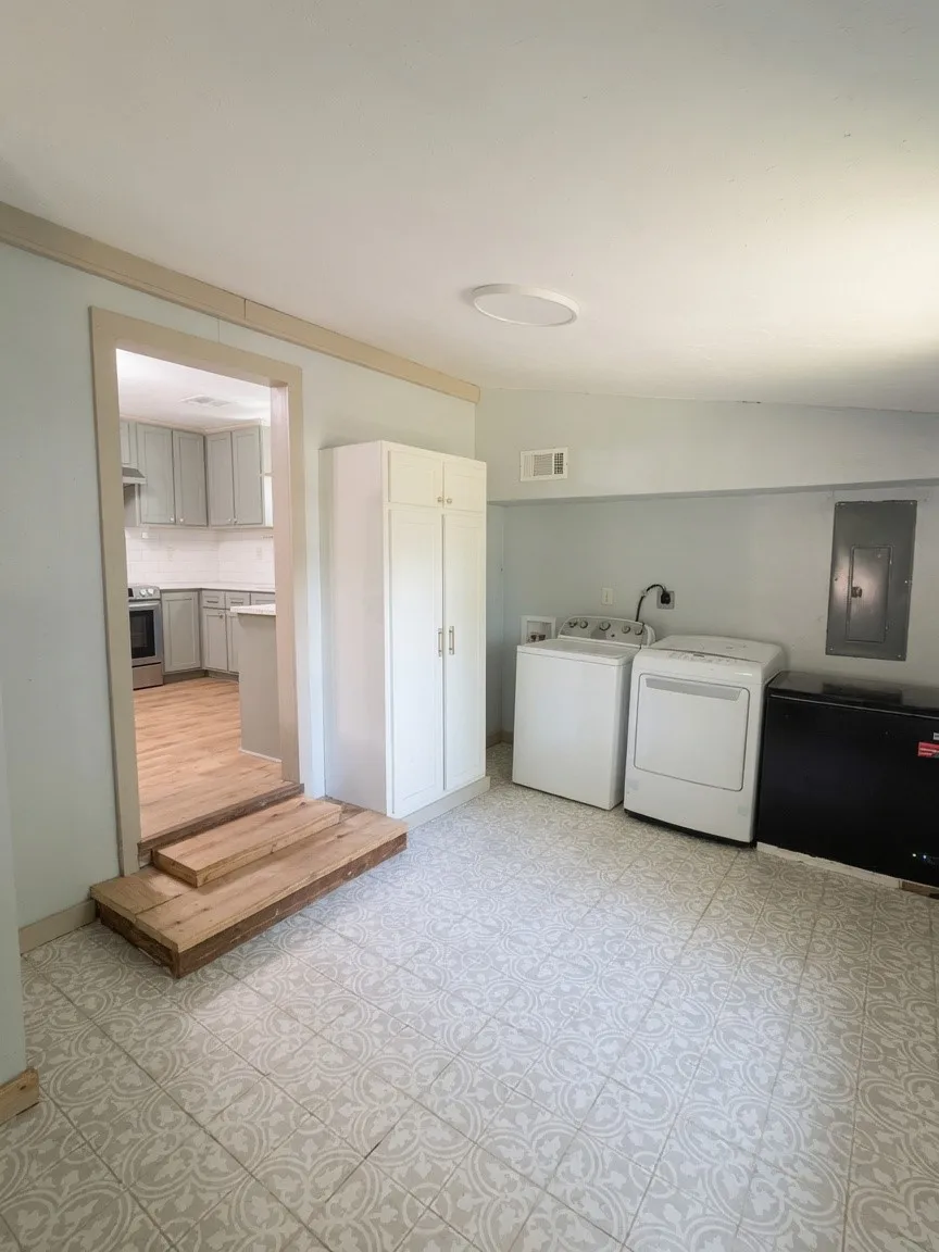 Laundry area featuring patterned tile flooring, a built-in storage cabinet, and light blue wall tones