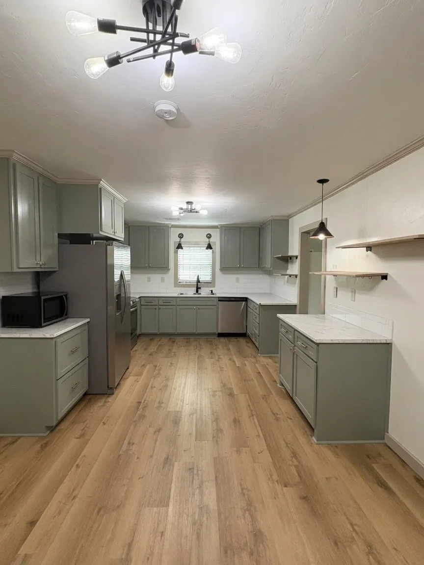 Spacious kitchen featuring extensive cabinetry, light wood-finish flooring, white countertops, and modern lighting fixtures