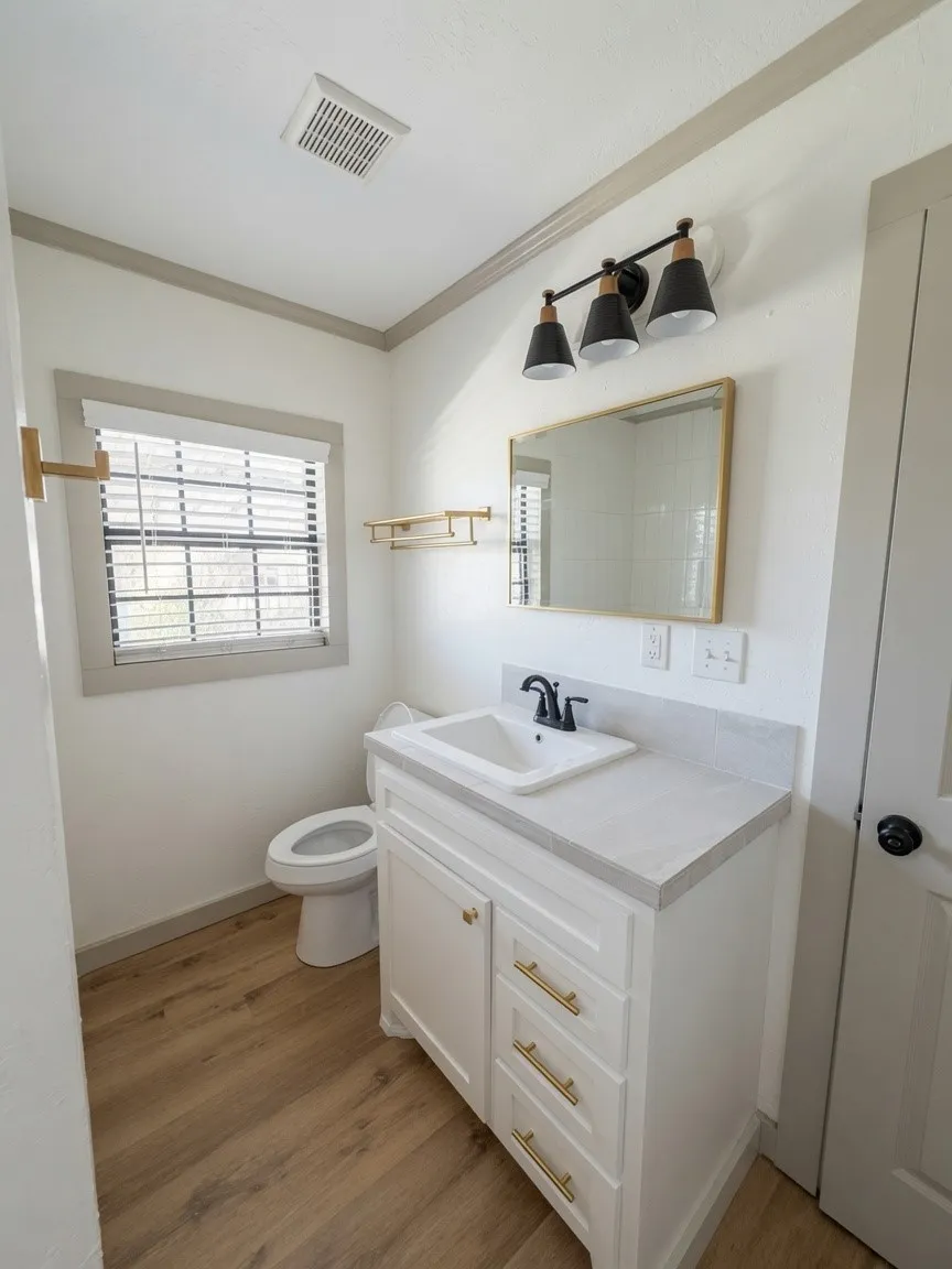 Bathroom featuring a white vanity with gold-tone hardware, a rectangular undermount sink, and a light-toned countertop