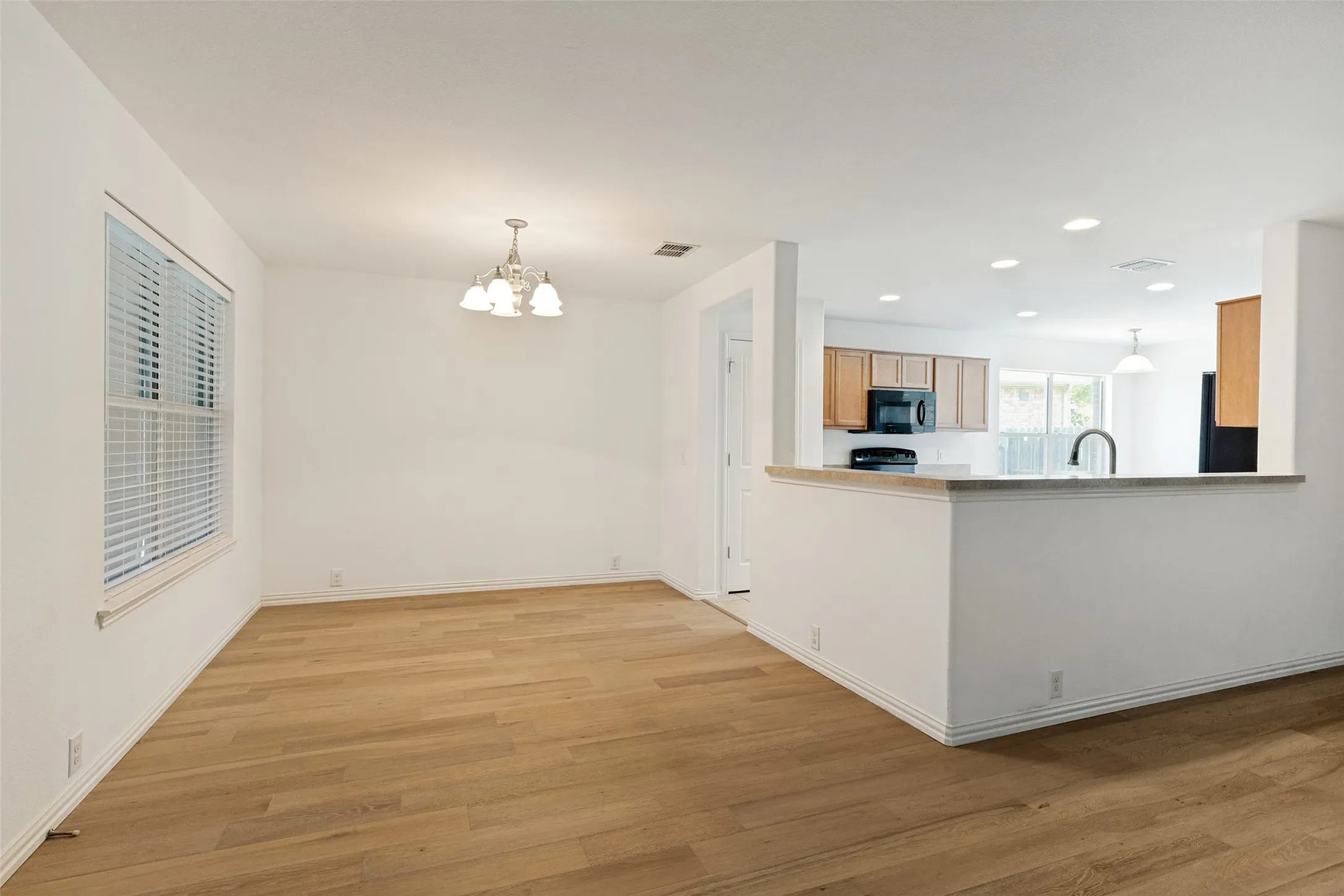 Spacious dining area overlooking the kitchen with light wood-finish flooring