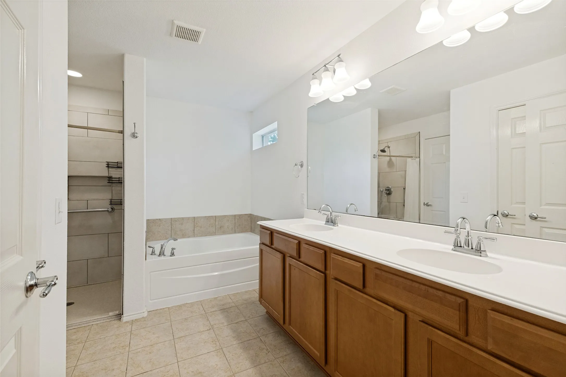 Spacious bathroom featuring a double vanity with ample storage, a large mirror, and overhead lighting