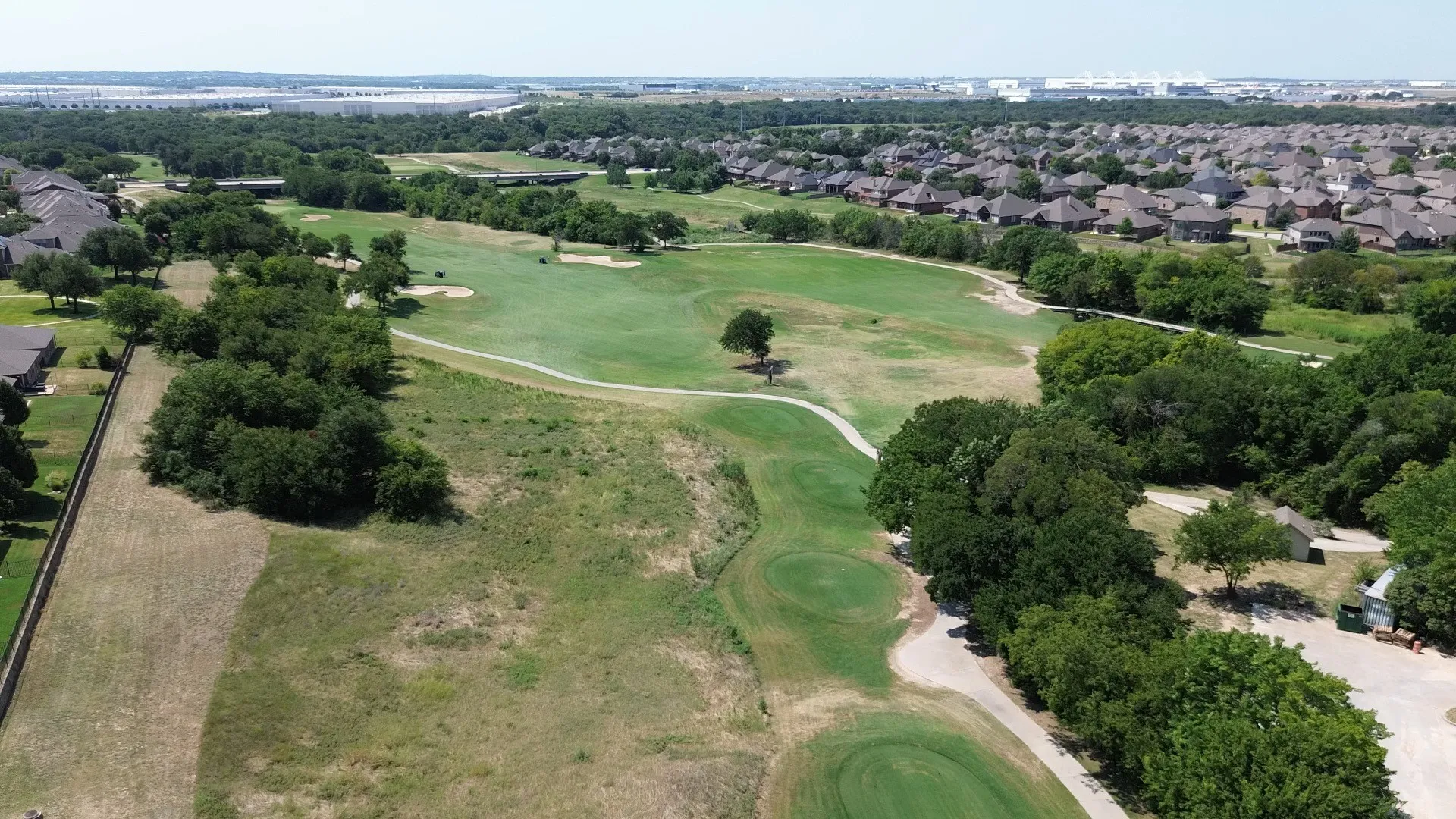 Expansive aerial View of Champions GC showcasing multiple greens and sand traps, surrounded by mature trees