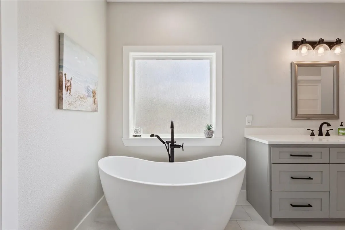 Freestanding soaking tub with a contemporary matte black floor-mounted faucet