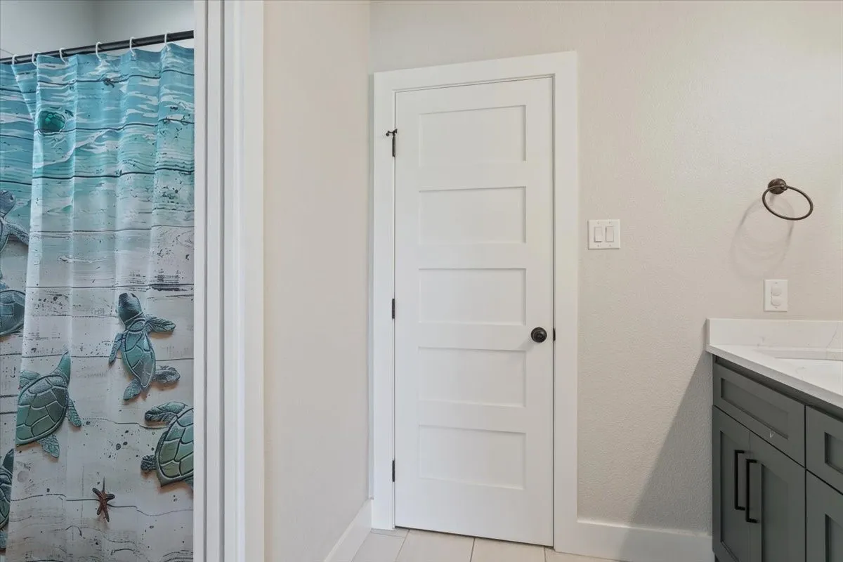 White paneled door with dark hardware, alongside a vanity featuring a light countertop and dark cabinetry