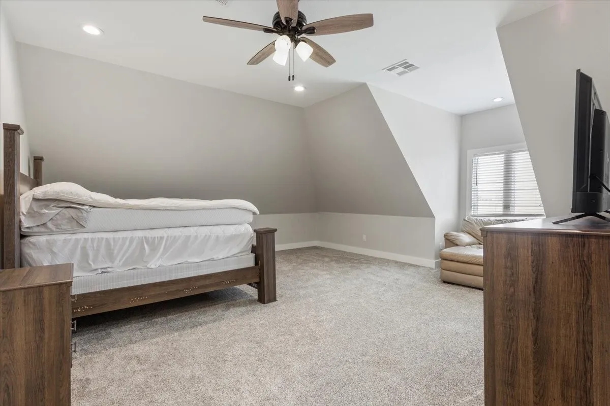 Carpeted room featuring a ceiling fan with integrated lighting, recessed lighting, and a window with blinds