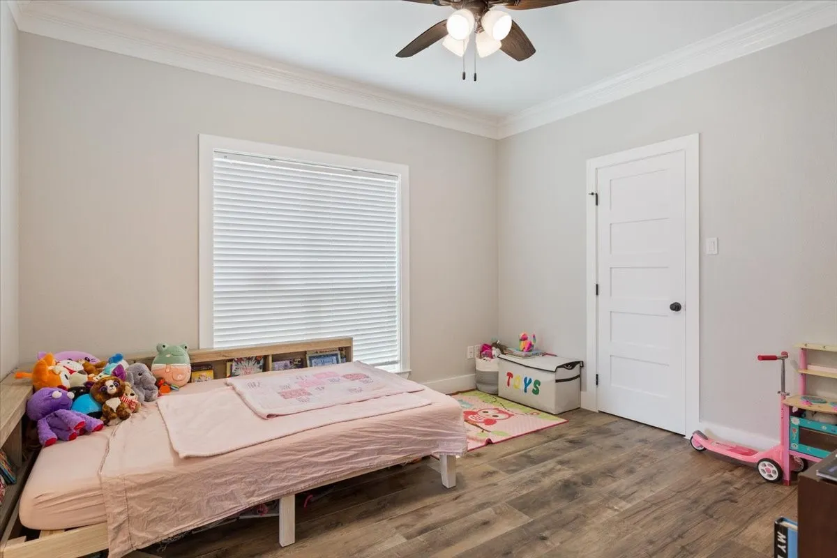 Interior room featuring wood-finish flooring, a white trim window with blinds, and a white interior door