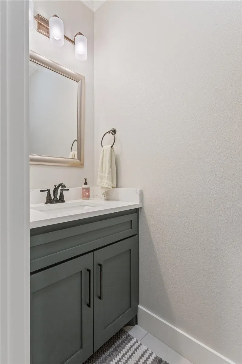 Powder room featuring a gray vanity with an integrated sink, a white countertop, and dark-toned hardware