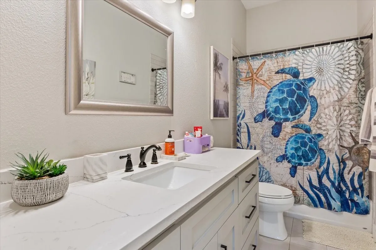 Bathroom featuring a spacious vanity with a white countertop and undermount sink, dark bronze-finish faucet, framed mirror, and a full bathtub with shower
