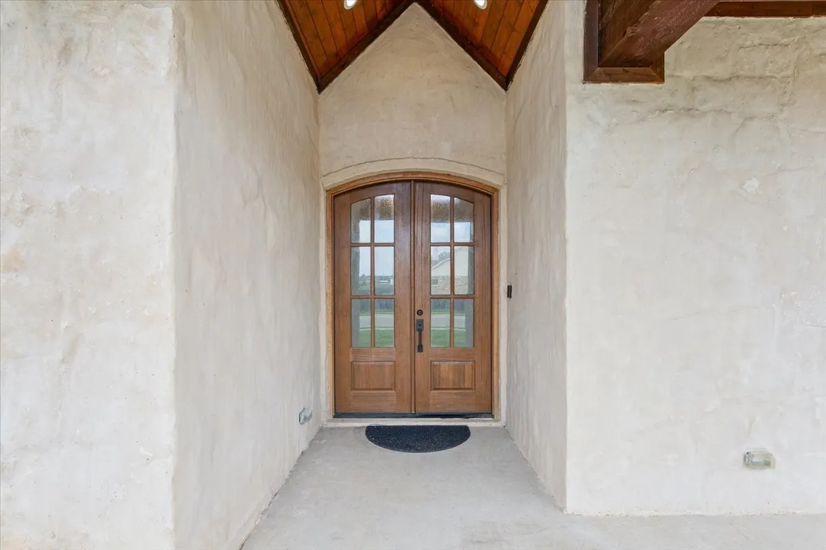 Arched double-door entry with glass panes and wood paneling