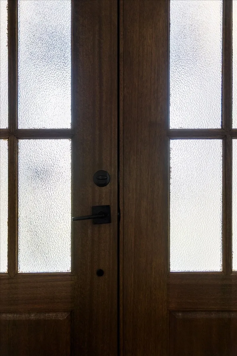 Double entry doors featuring dark wood-finish panels and textured glass inserts