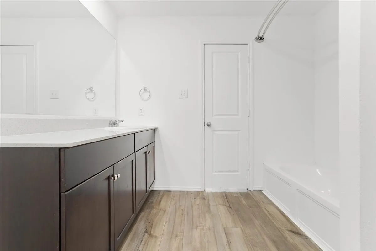 Spa-inspired primary bathroom featuring a dark wood vanity with ample storage, white quartz countertop, and brushed nickel hardware