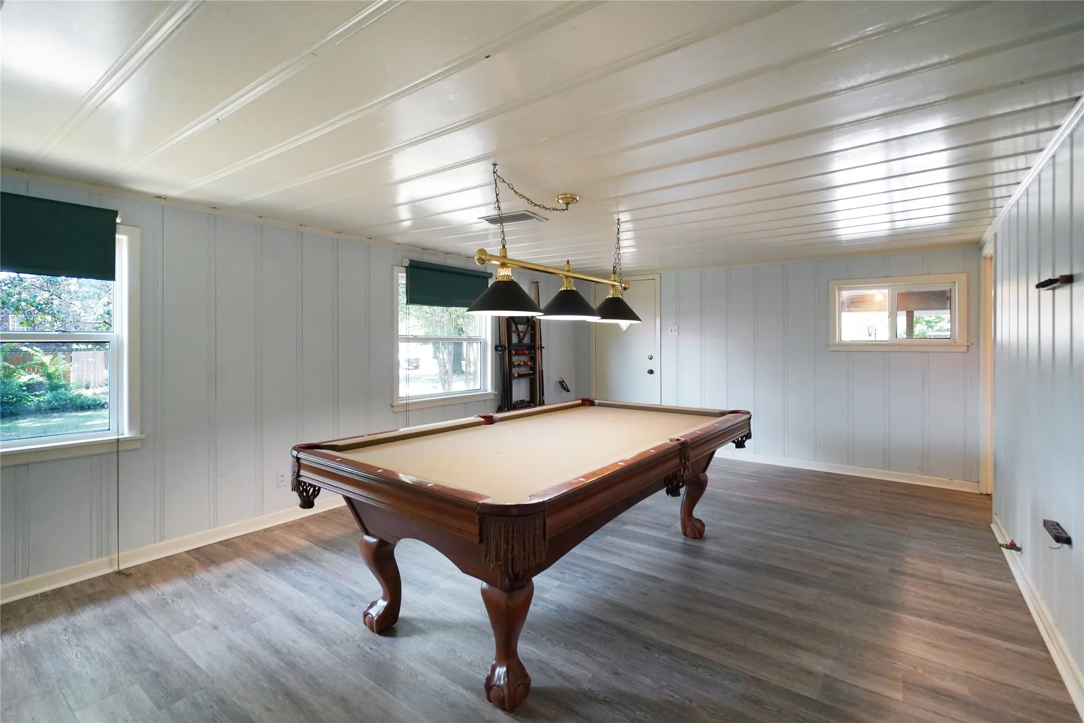 Spacious recreation room featuring plank-style flooring, white paneled walls, and a white plank ceiling