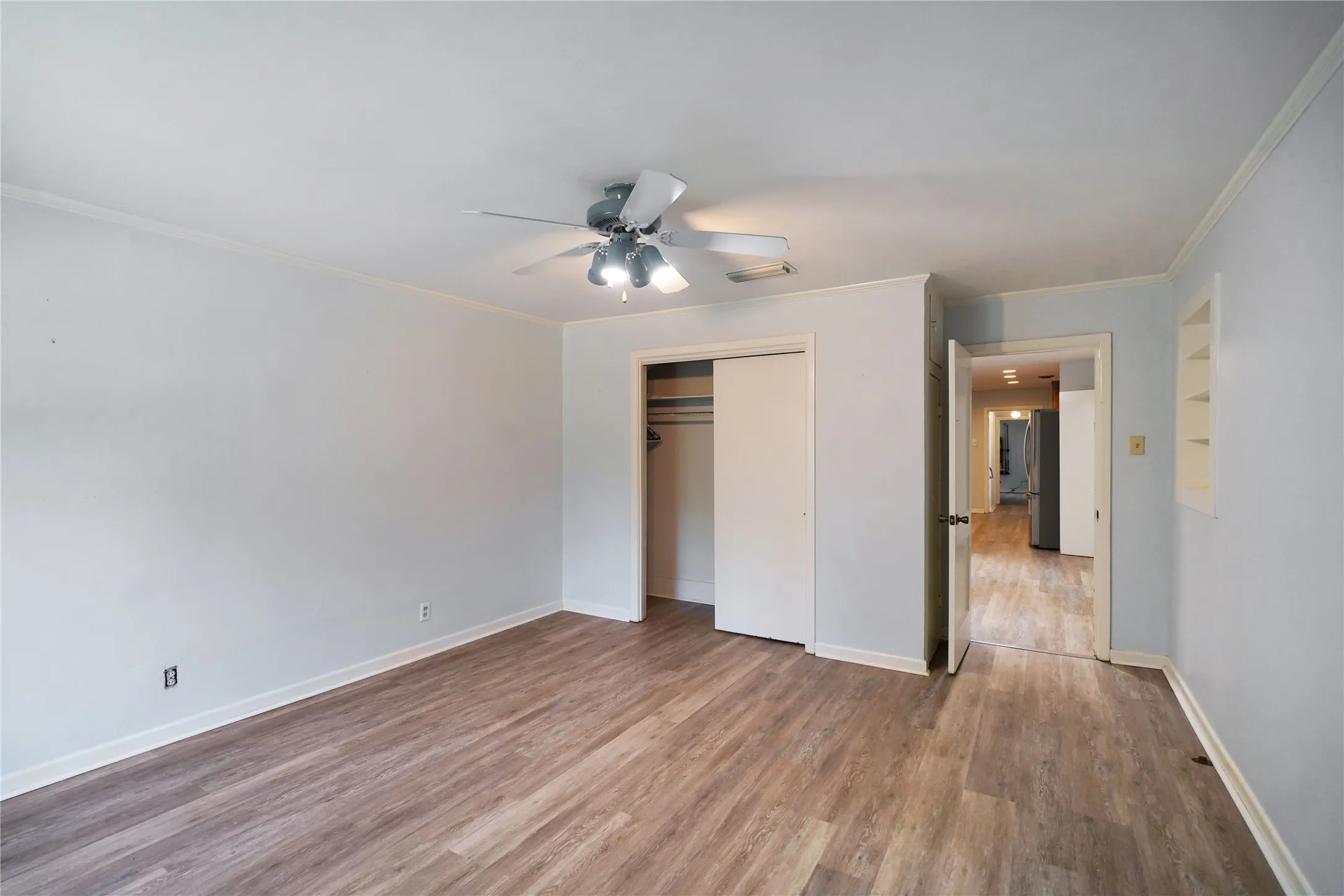 Spacious room featuring wood-finish flooring, white baseboards, and a ceiling fan with integrated​​‌​​​​‌​​‌‌​‌‌​​​‌‌​‌​‌​‌​​​‌​​ lighting