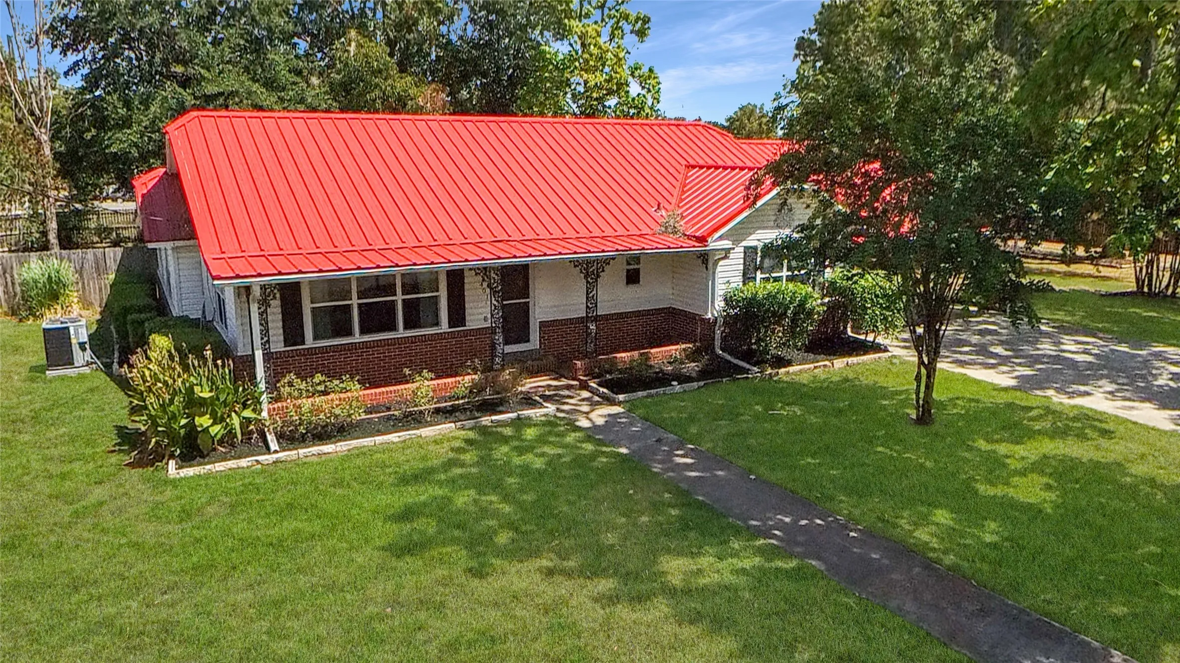 Red metal roof, white siding, and brick facade