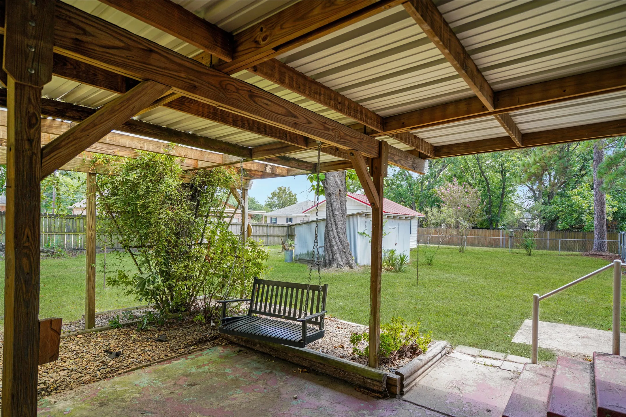 Covered patio with exposed wood beams and a corrugated metal roof