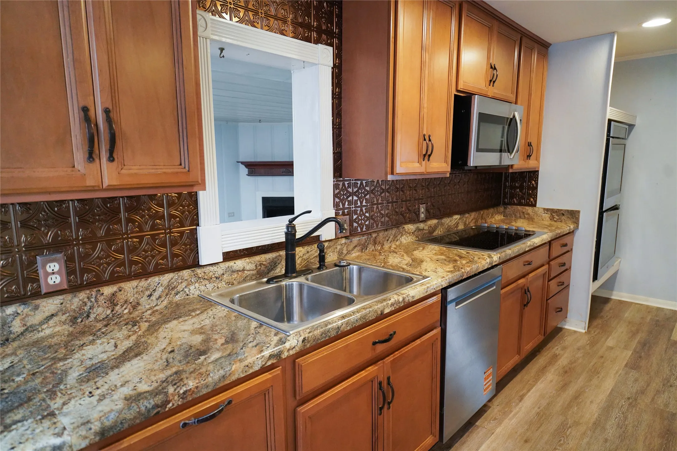 Kitchen featuring warm-toned cabinetry, a stainless steel double basin sink, and an integrated cooktop