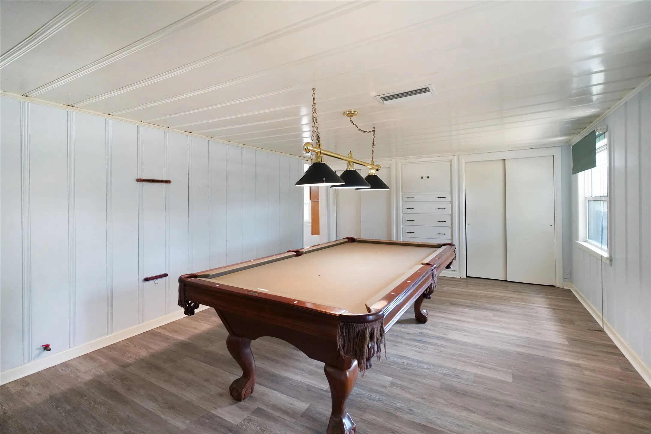 Room featuring wood-finish flooring, white vertical paneling, and a panelled ceiling