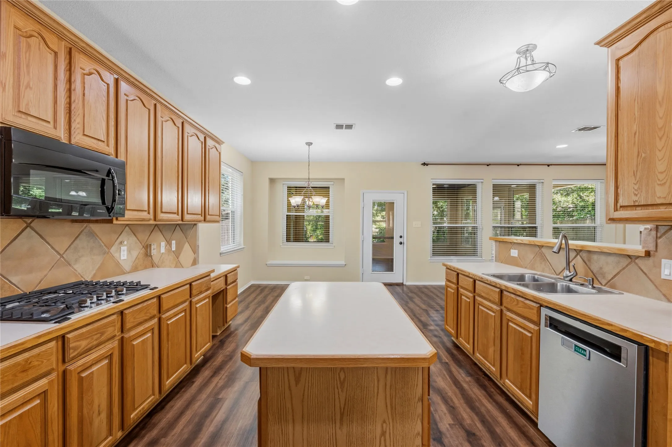 Open-concept kitchen with wood-finish flooring, a central island, recessed lighting, and a tiled backsplash