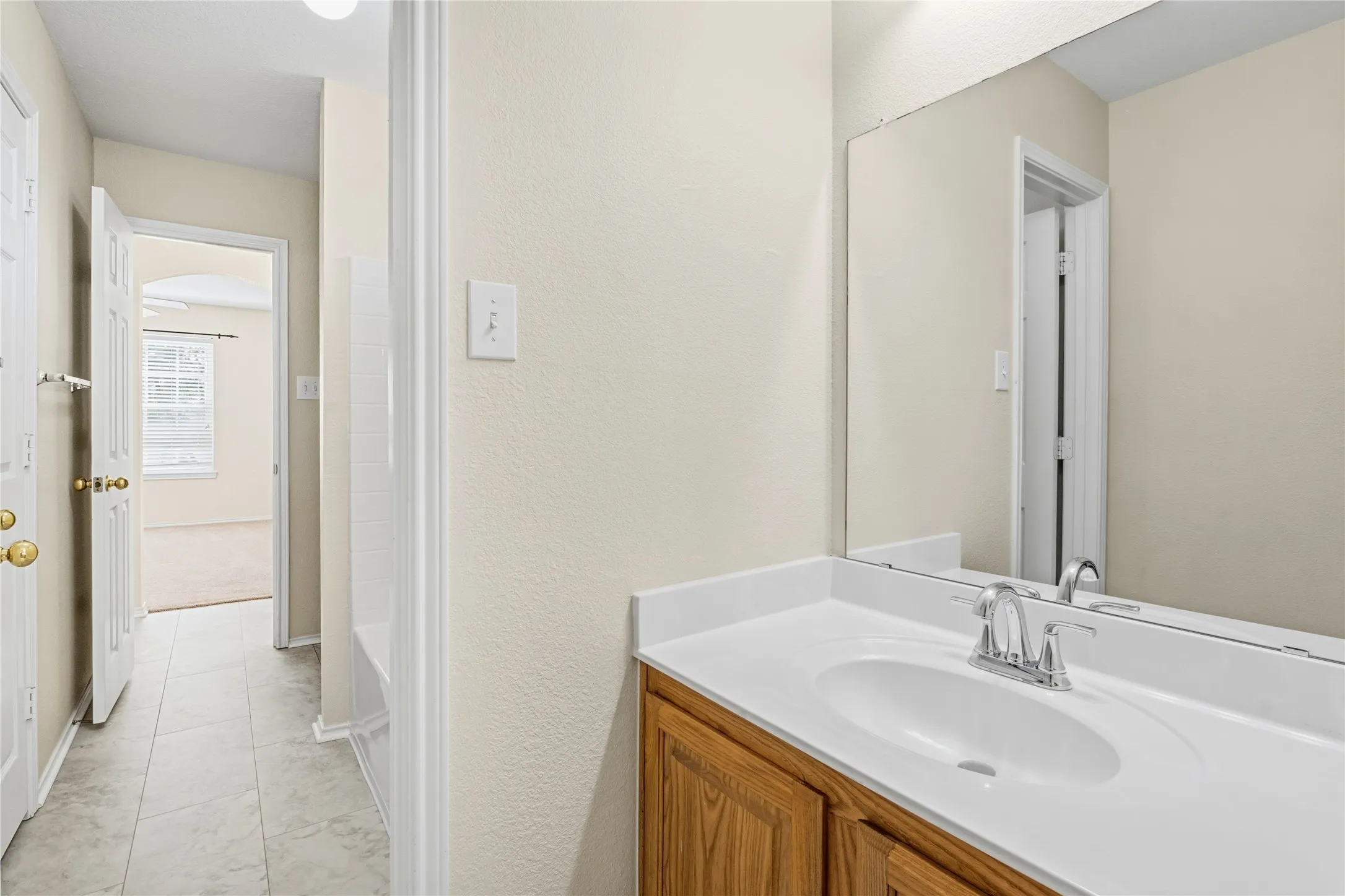 Bathroom vanity featuring a white solid-surface countertop with an integrated sink, polished chrome faucet, and a large wall-mounted mirror