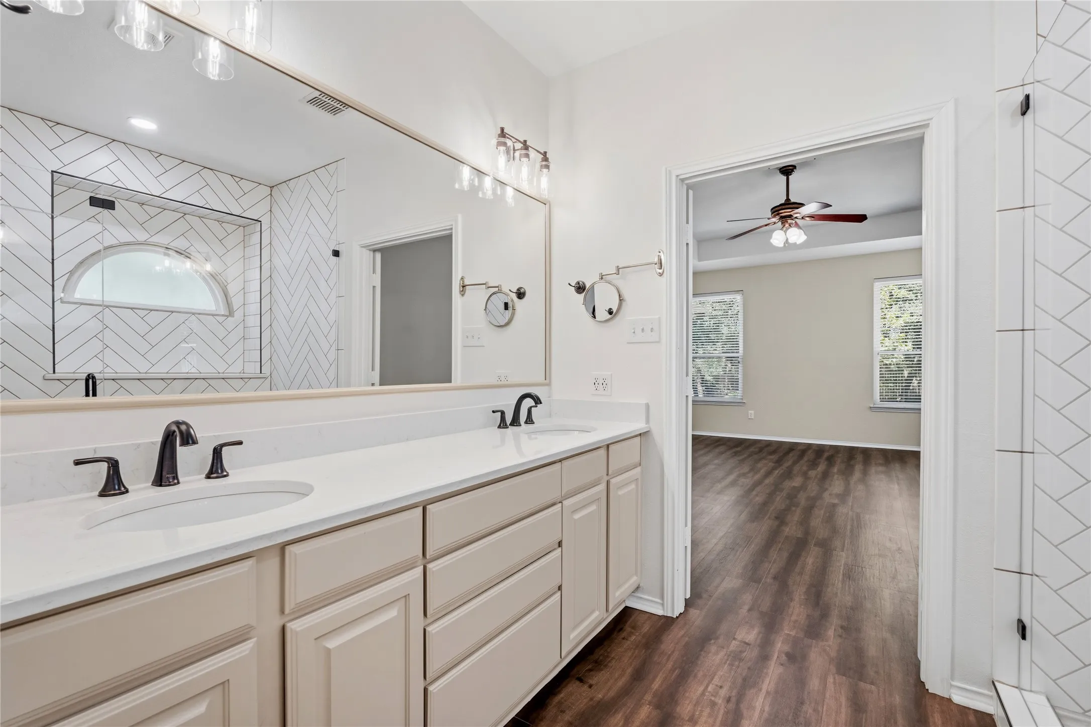 Bathroom vanity featuring dual undermount sinks with black fixtures, a white countertop, and light-toned cabinetry