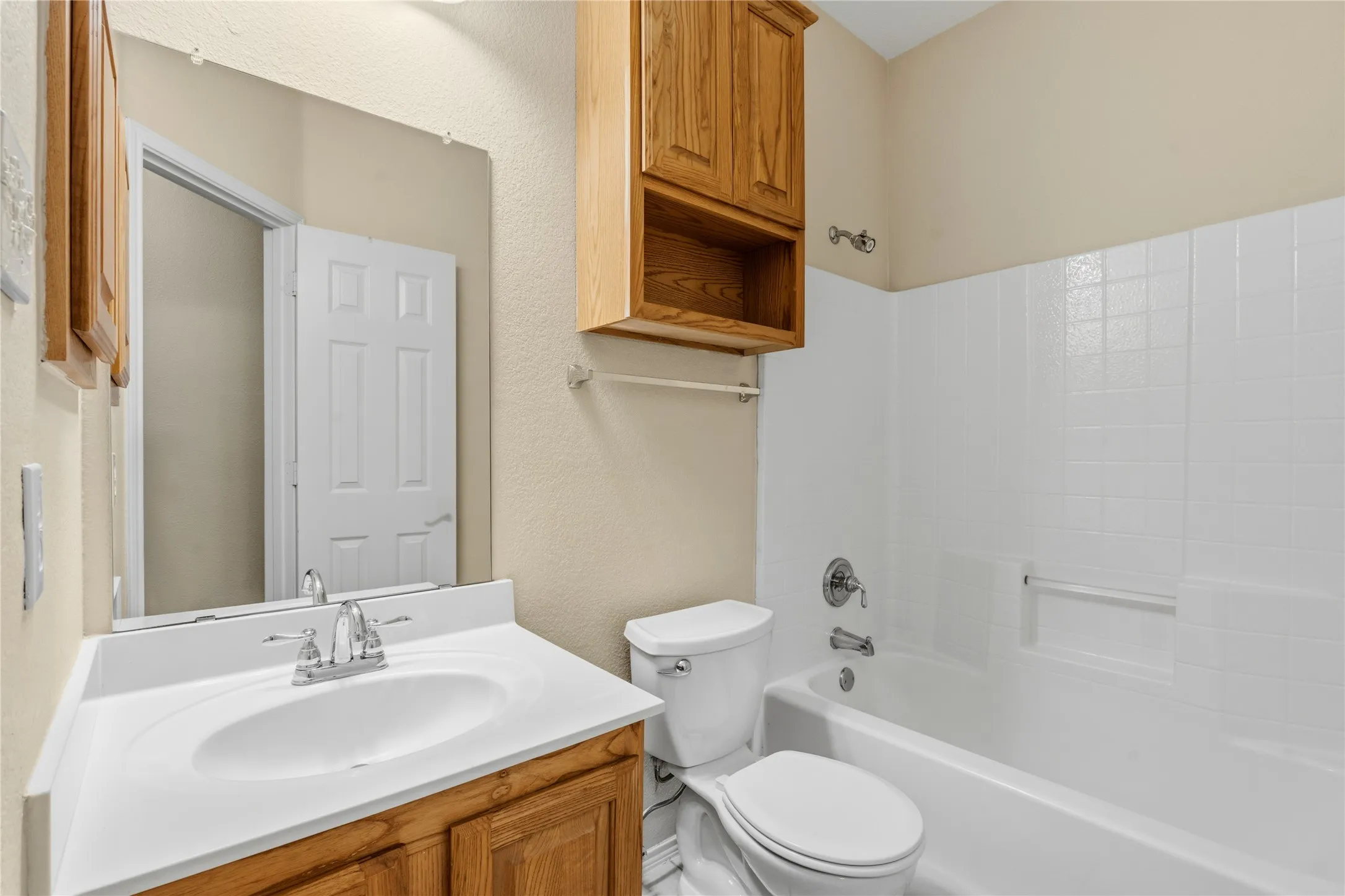 Full bathroom featuring a white vanity with integrated sink, chrome faucet, and wood-finish cabinetry