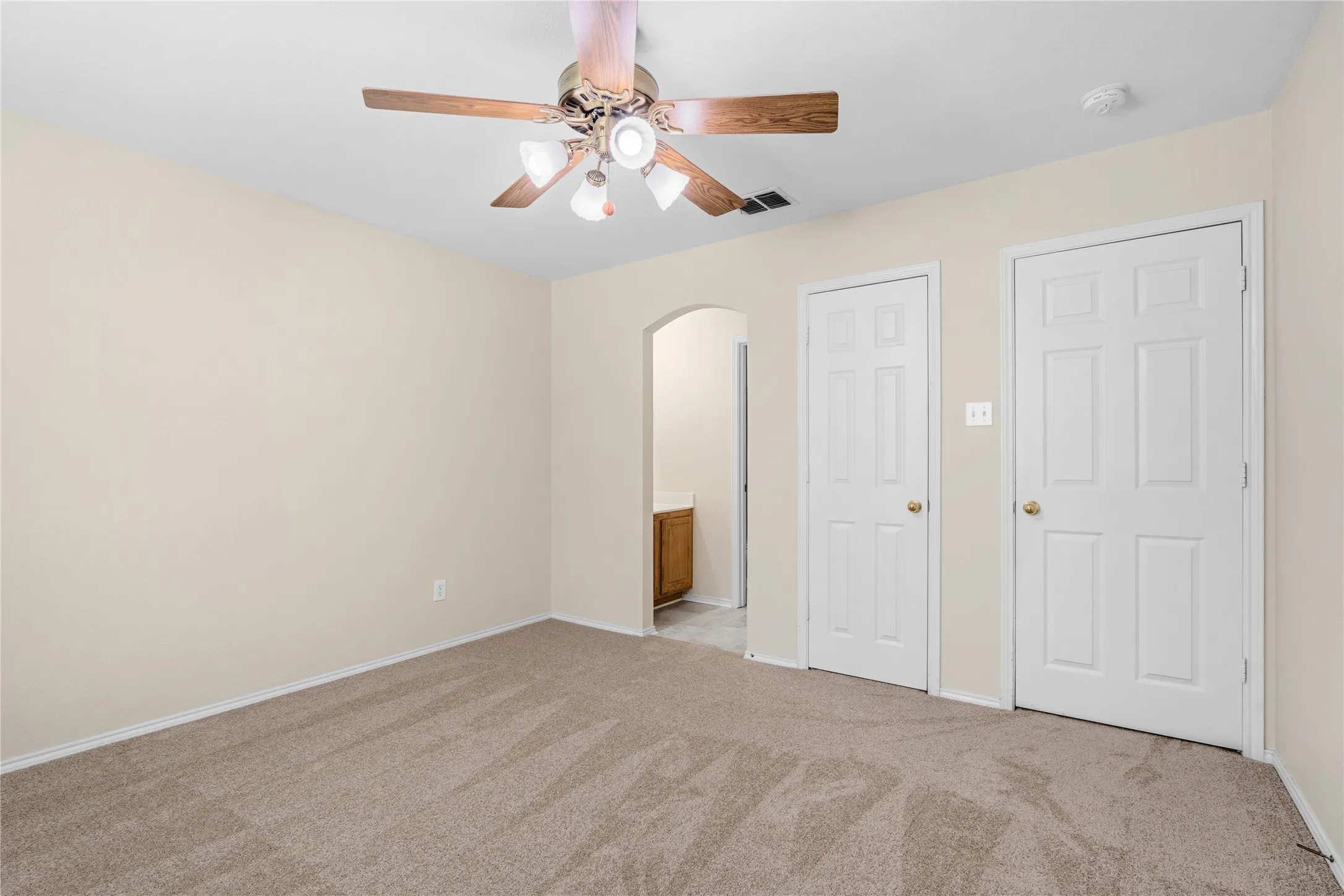 Carpeted interior space featuring a ceiling fan with integrated lighting, a neutral wall color, and white paneled doors