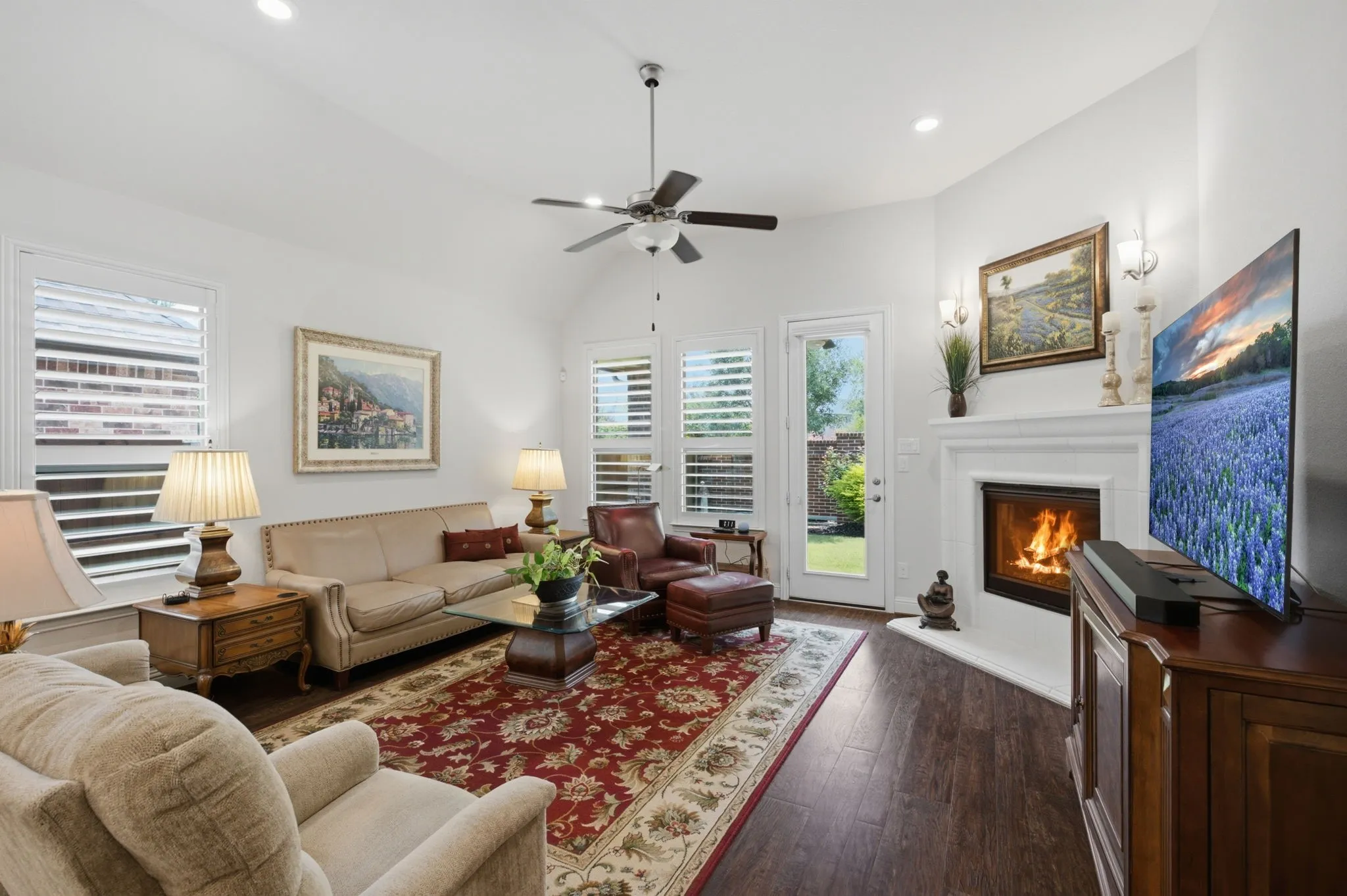 Mantle has built in Sconces, Well Appointed with Plantation Shutters, wood flooring and ceiling fan. Door to the patio.