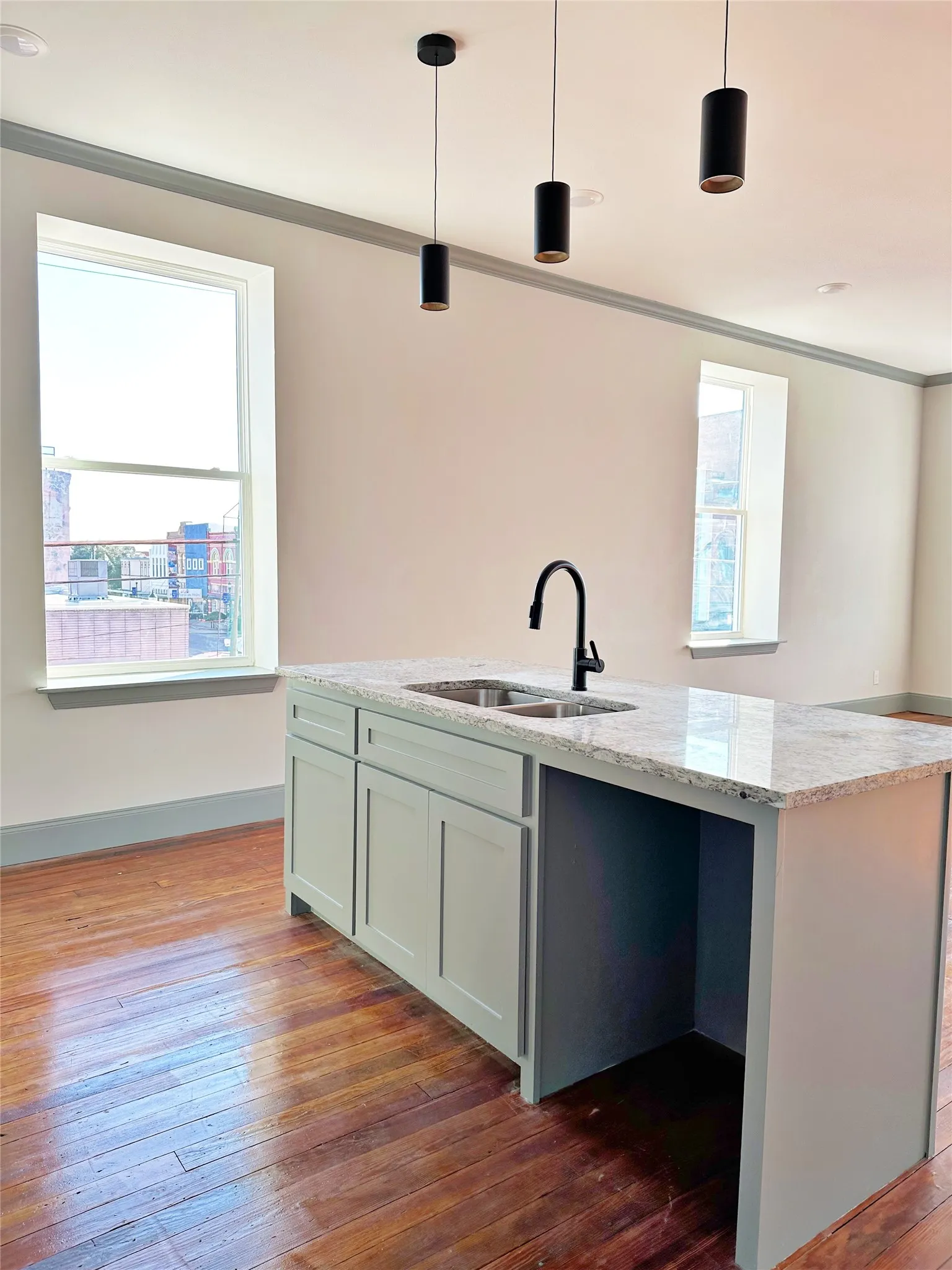Central kitchen island featuring a light-toned countertop with an undermount double-basin sink and a matte black gooseneck faucet