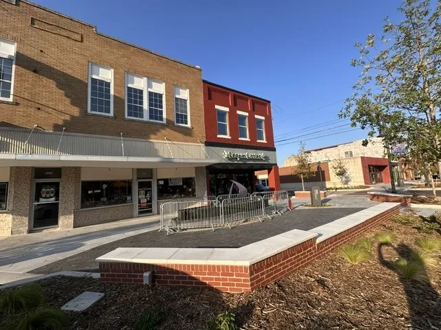 Brick facade with multiple large windows, ground-floor retail space, and a red brick knee wall