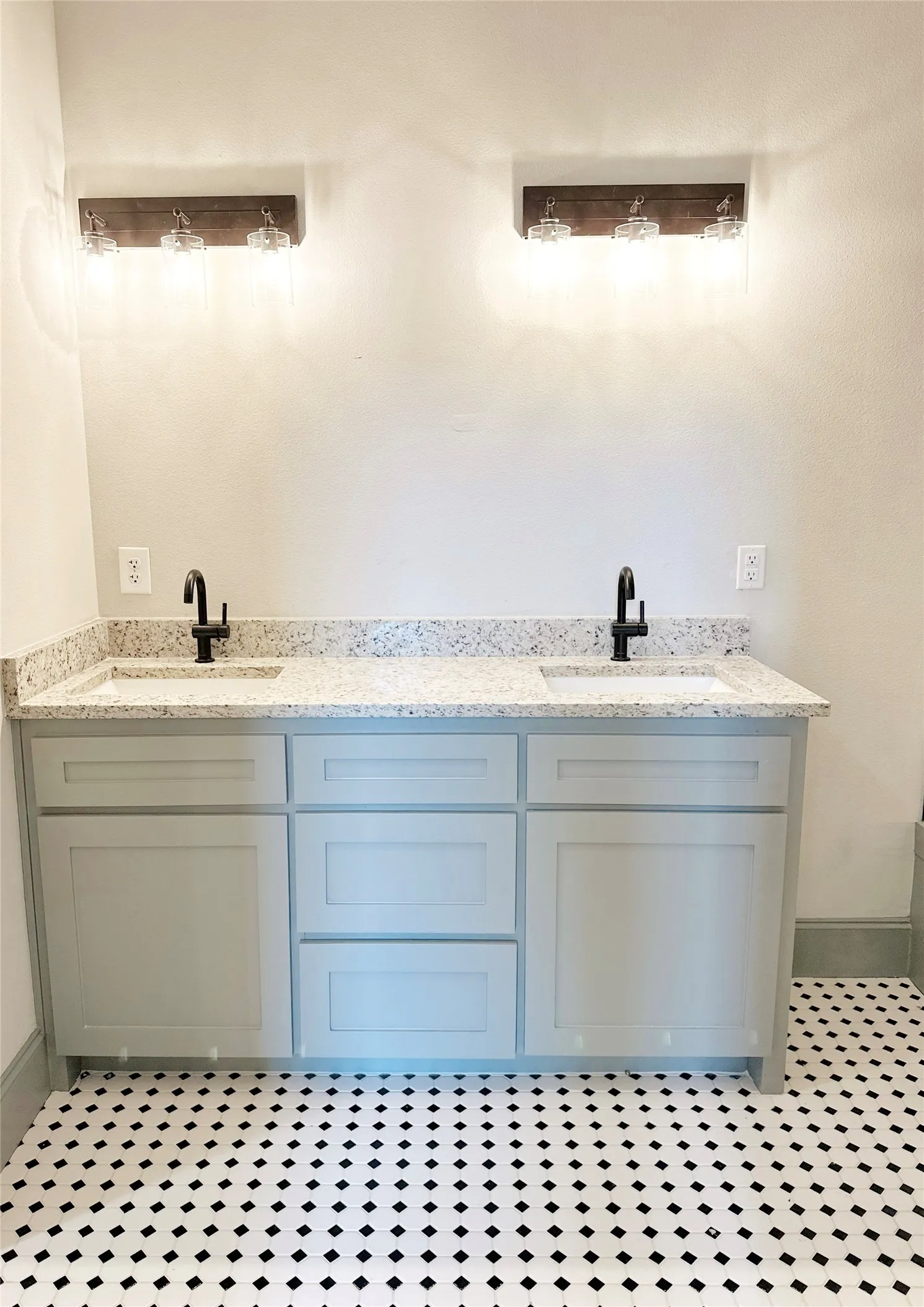 Dual vanity with gray shaker cabinetry, undermount sinks, and speckled countertop