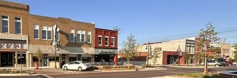 Brick facade commercial buildings featuring storefront windows and sidewalk access